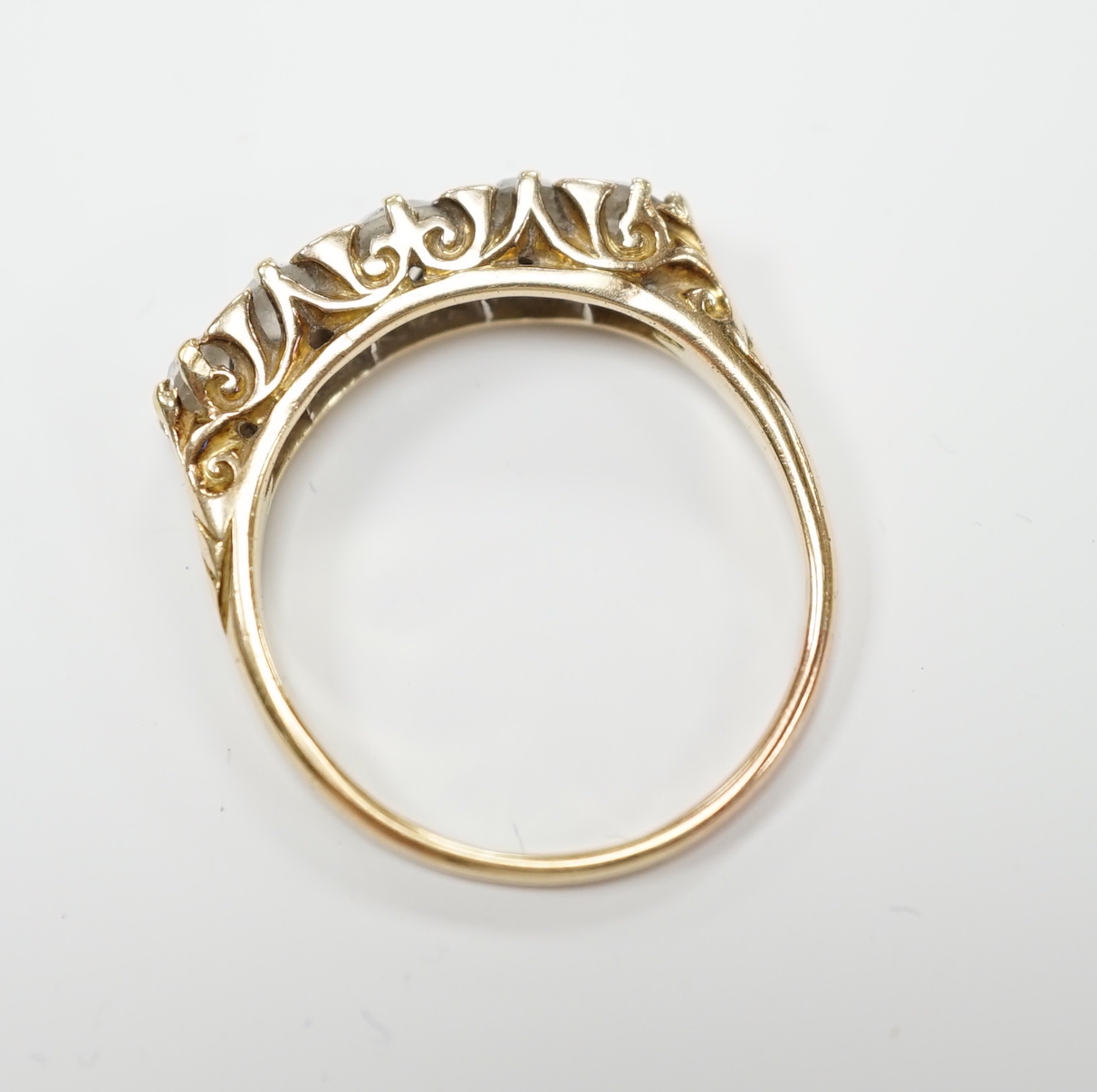 A yellow metal and graduated five stone diamond set half hoop ring, size Q, gross weight 3.9 grams.
